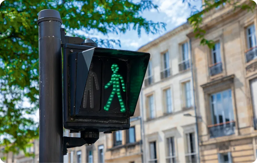 Feu piéton vert allumé, fond urbain flou.