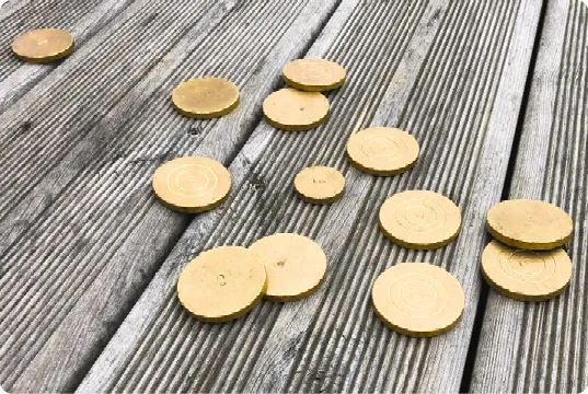 Pièces dorées éparpillées sur planches en bois gris.