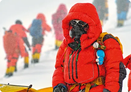 Explorateurs en tenues rouges contre le froid avancent dans la neige.