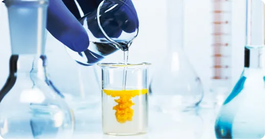 Pipette ajoutant liquide dans un bécher avec précipité jaune, en laboratoire.