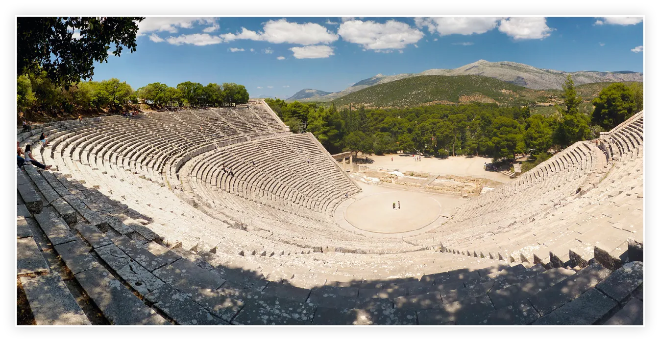 Vue du théâtre d'Épidaure (Grèce) en 2013, montrant les gradins de pierre en demi-cercle et l'orchestra, avec en arrière-plan des collines boisées.