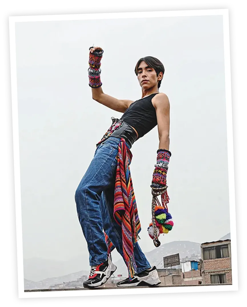 Joven posando con una vestimenta que fusiona elementos urbanos modernos con accesorios tradicionales andinos.