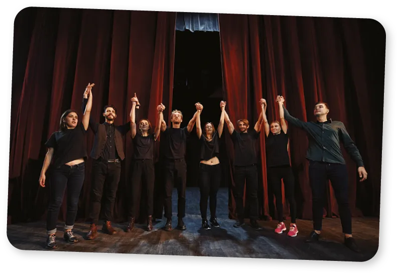 A group of actors on a stage with red curtains.