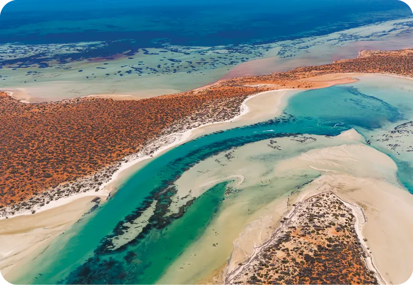 Vue Aérienne de Shark Bay, Australie, présentant des eaux turquoise vives, des plages de sable et des paysages de terre rouge.
