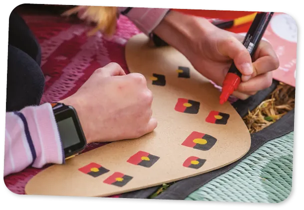 Mains avec un crayon coloré, boomerang de papier peint d'enfant avec le drapeau aborigène australien à l'événement de la communauté indigène