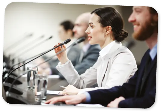 Un des jeunes politiciens parlant au micro parmi d'autres participants à la conférence.