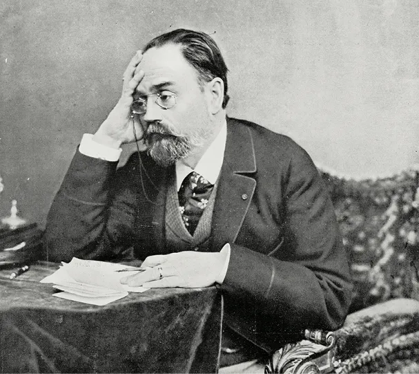 Photographie d'Émile Zola, écrivain français, assis à son bureau en 1902. Il lit des papiers, la main sur le visage, en signe de réflexion.