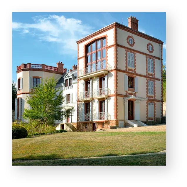 Photographie de la Maison Zola, musée Dreyfus : élégante demeure beige à plusieurs étages, jardin verdoyant.
