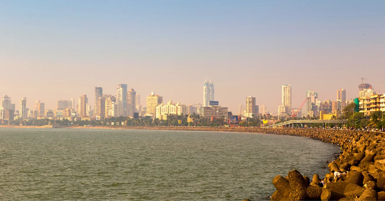 Photo panoramique de Mumbai : Skyline côtière avec immeubles, digue et mer.