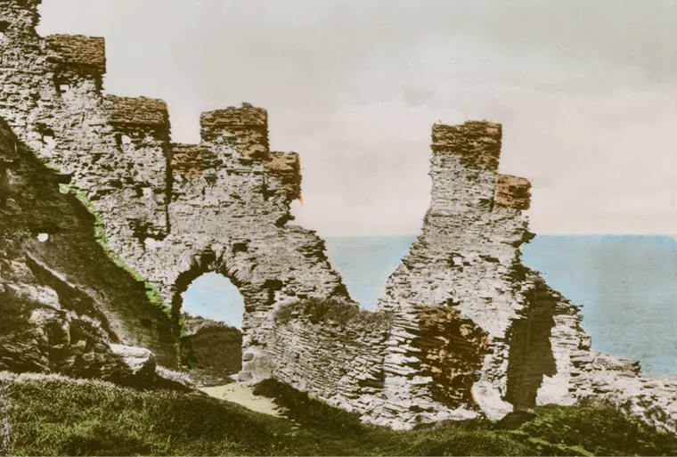 Photographie des ruines du château de Tintagel en Cornouailles.  Murs de pierre, arche et vue sur la mer.