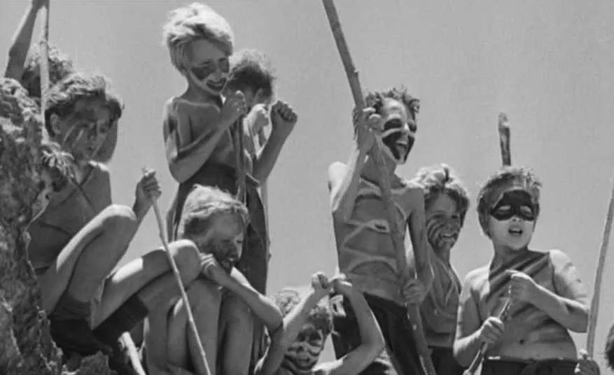 Photographie : enfants peints, tenant des bâtons, évoquant une scène tribale. Adaptation cinématographique de &quotSa majesté des mouches"?