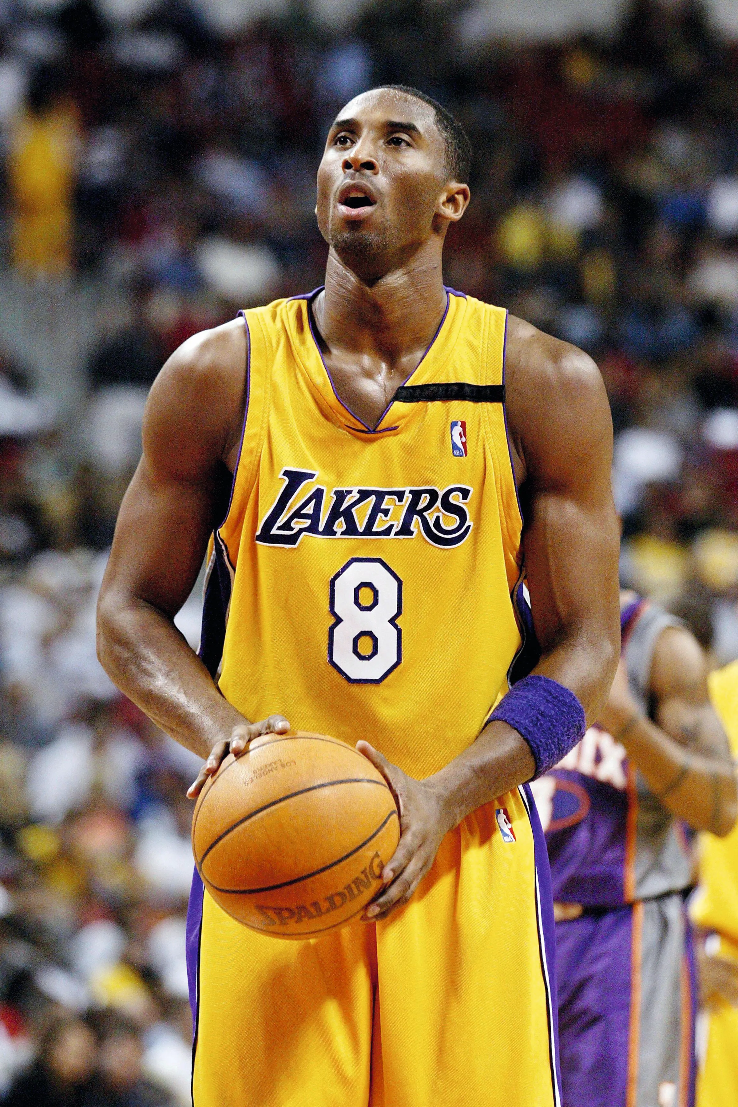 Photographie de Kobe Bryant, joueur des Lakers, tenant un ballon de basket. Il porte le maillot jaune et pourpre numéro 8. Match de NBA.