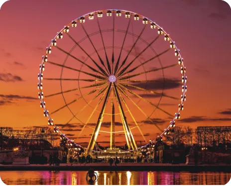 Roue Ferris éclairée au coucher du soleil, ciel coloré et roue Ferris.