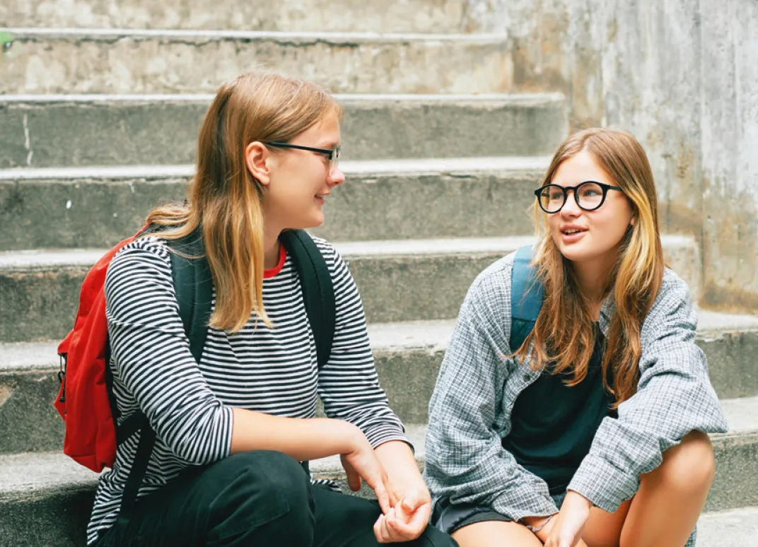 Deux jeunes filles assises sur des marches d'escalier discutent