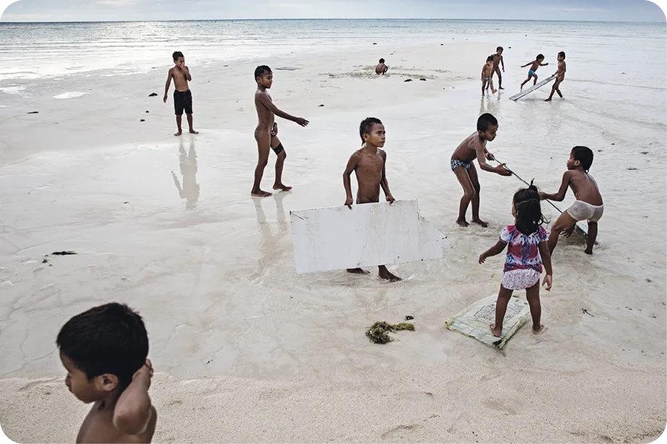 Young children playing on the beach on the island of Tarawa, the capital of the Republic of Kiribati. The people of Kiribati are under pressure to relocate due to sea level rise