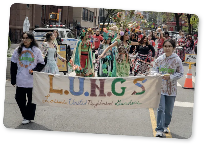 Two girls carrying a banner for Loisaida United Neighborhood Gardens (LUNGS), lead the 2024 Spring Awakening Parade marching through and out of Tompkins Square Park, New York, New York.