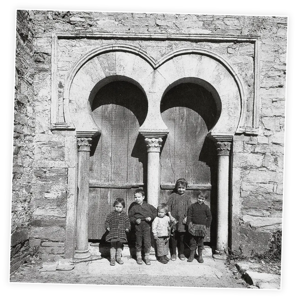 Niños delante de arcos de herradura mozárabe de Santiago de Peñalba, 1960.