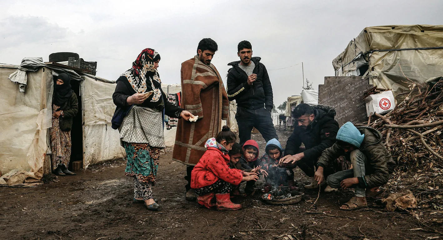 Photographie de réfugiés syriens autour d'un feu dans un camp près de la frontière libano-syrienne. Familles, enfants, froid.