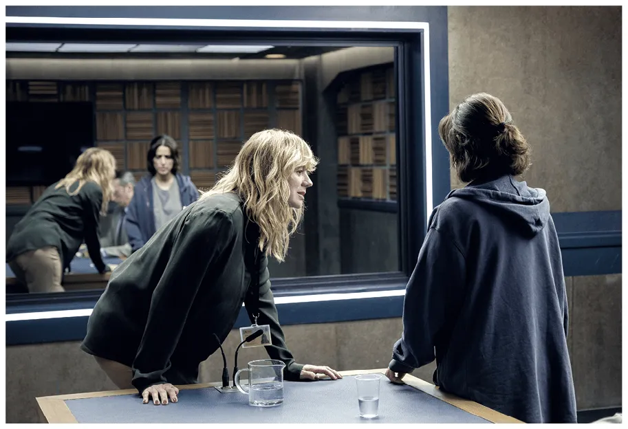 Photographie de la série Criminal, deux femmes s'interrogent dans une salle d'interrogatoire. Une femme penchée sur une table, l'autre debout, dos à la caméra.