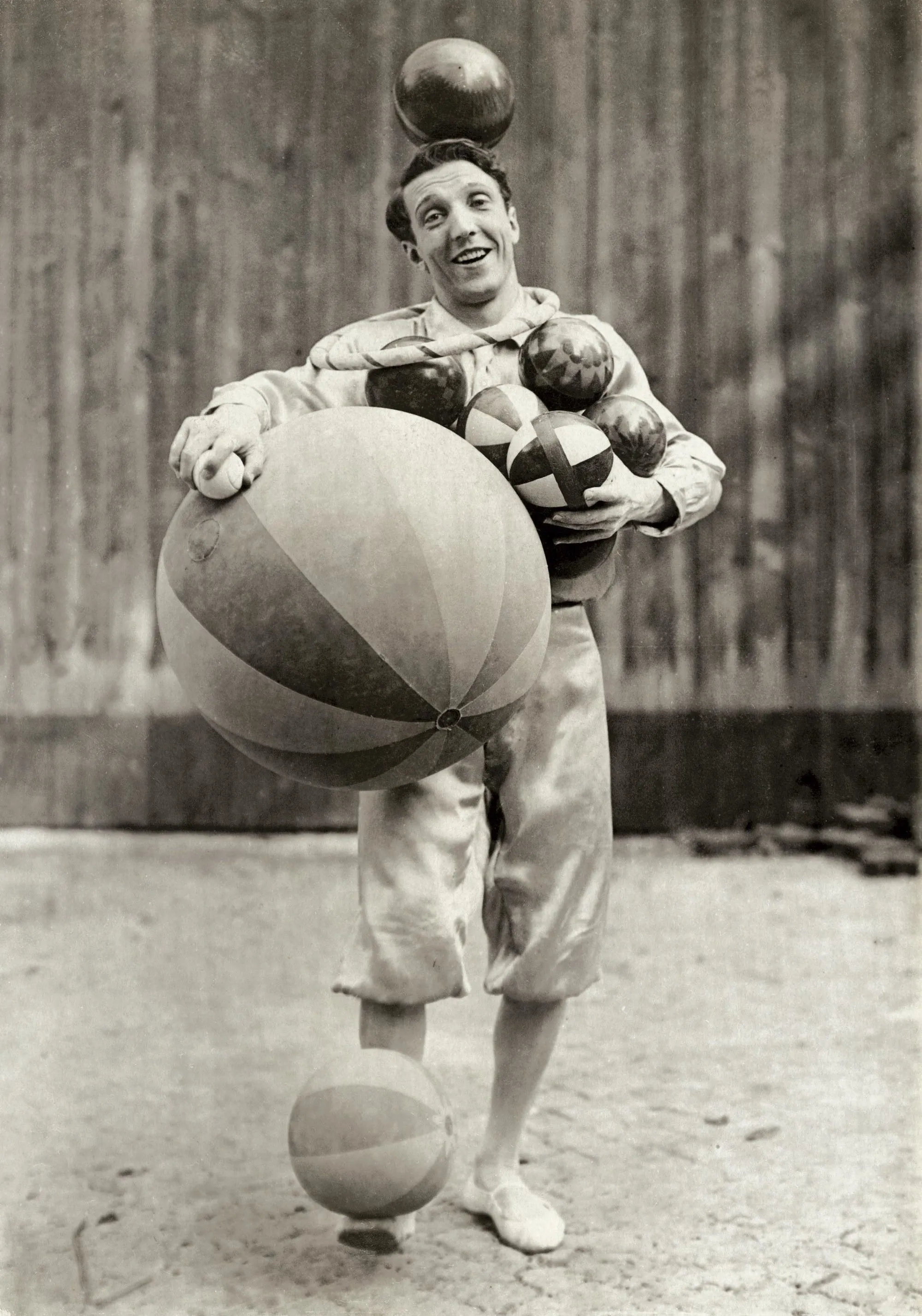 Photographie d'Enrico Rastelli, jongleur, manipulant plusieurs balles, dont une grande, avec une sur sa tête.