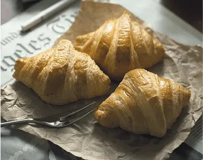 Photographie de trois croissants dorés disposés sur du papier kraft.