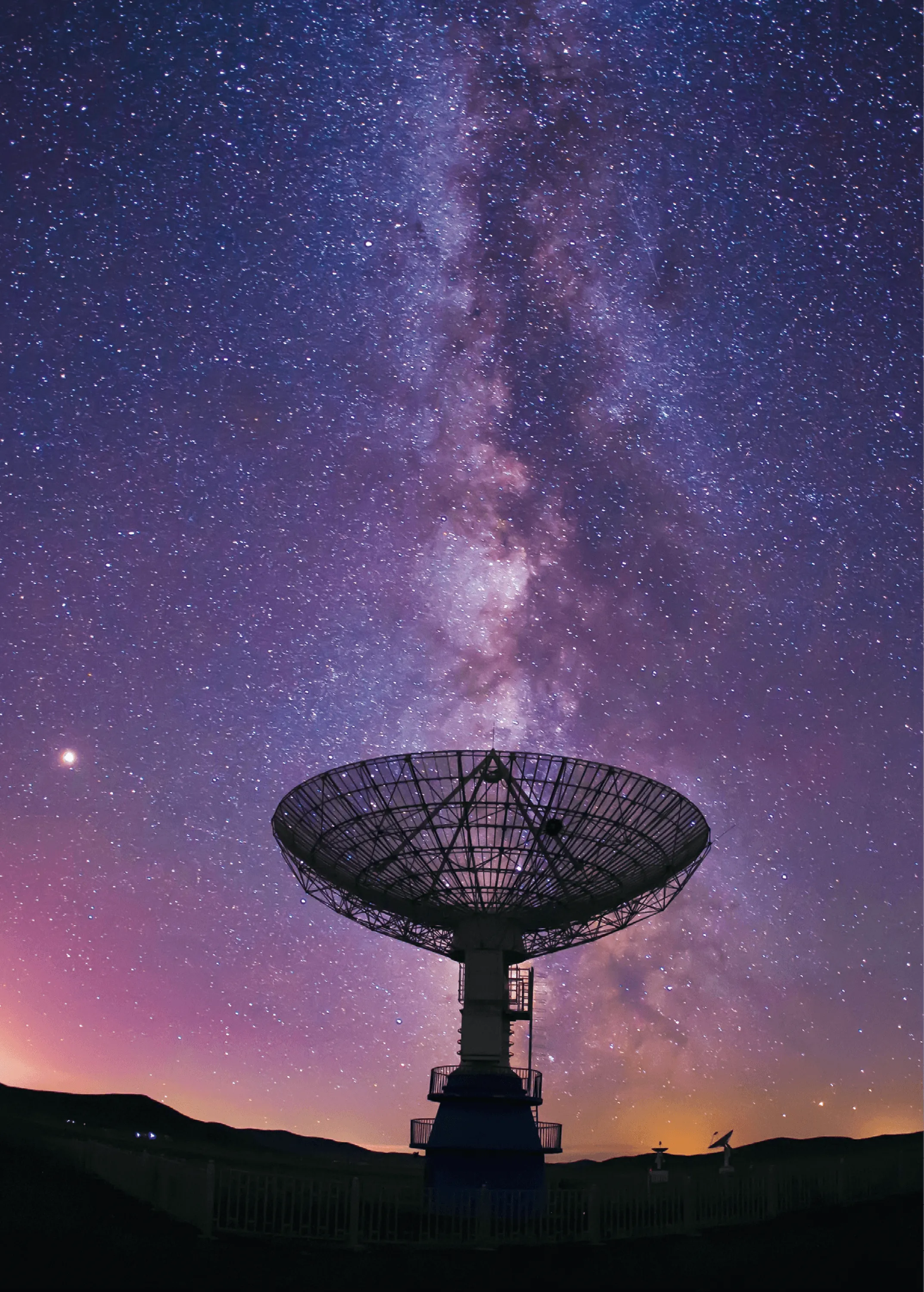 Photographie d'un radiotélescope et de la Voie Lactée la nuit