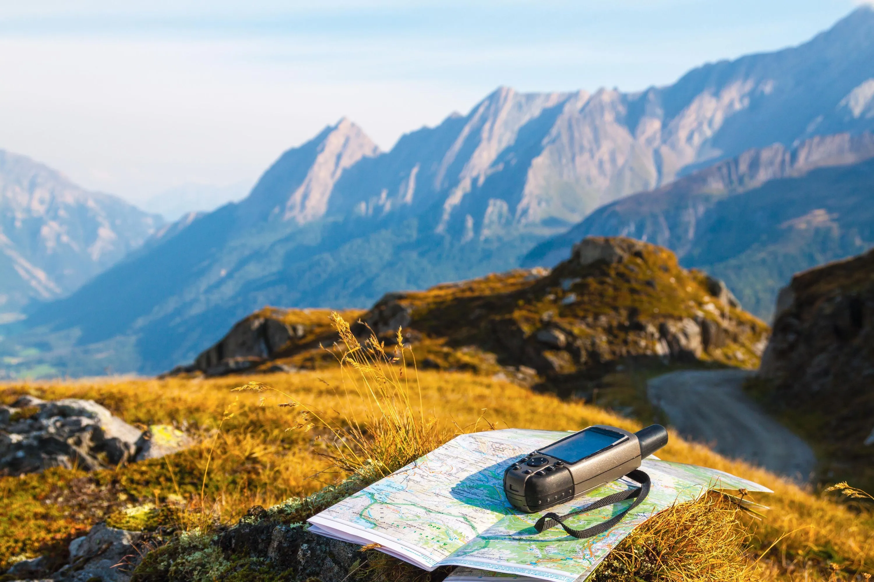 Photographie d'une carte topographique et d'un GPS sur un sommet montagneux. Randonnée en montagne.