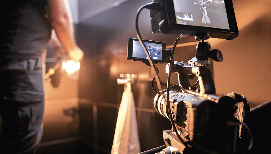 Photographie d'un tournage, caméra professionnelle filmant une scène, éclairage et cadreur visibles.