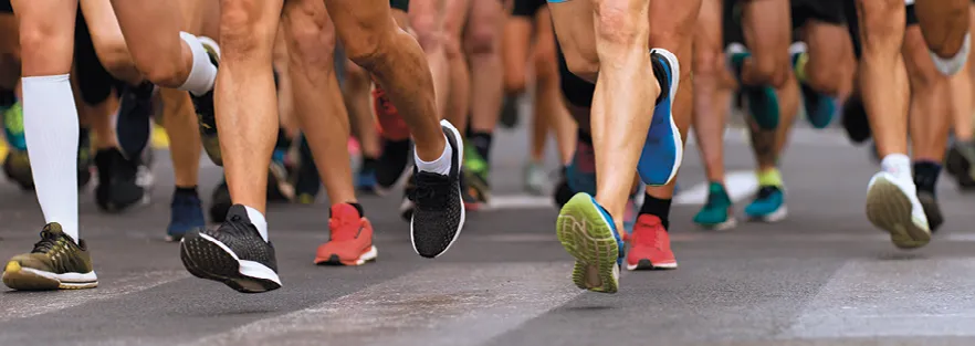 photo de nombreux bas de jambe de coureur en train de courir un marathon sur du béton