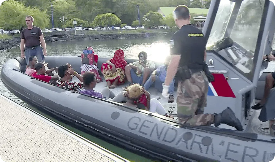 Photographie : gendarmes français interceptant des migrants dans une embarcation pneumatique à Mayotte.