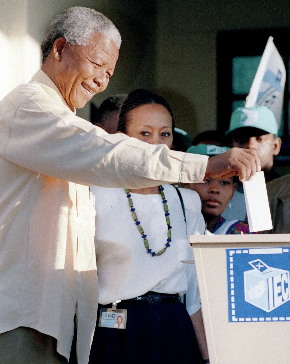 Photographie de 1994: Nelson Mandela, souriant, dépose son bulletin de vote dans une urne.  Élection historique en Afrique du Sud.