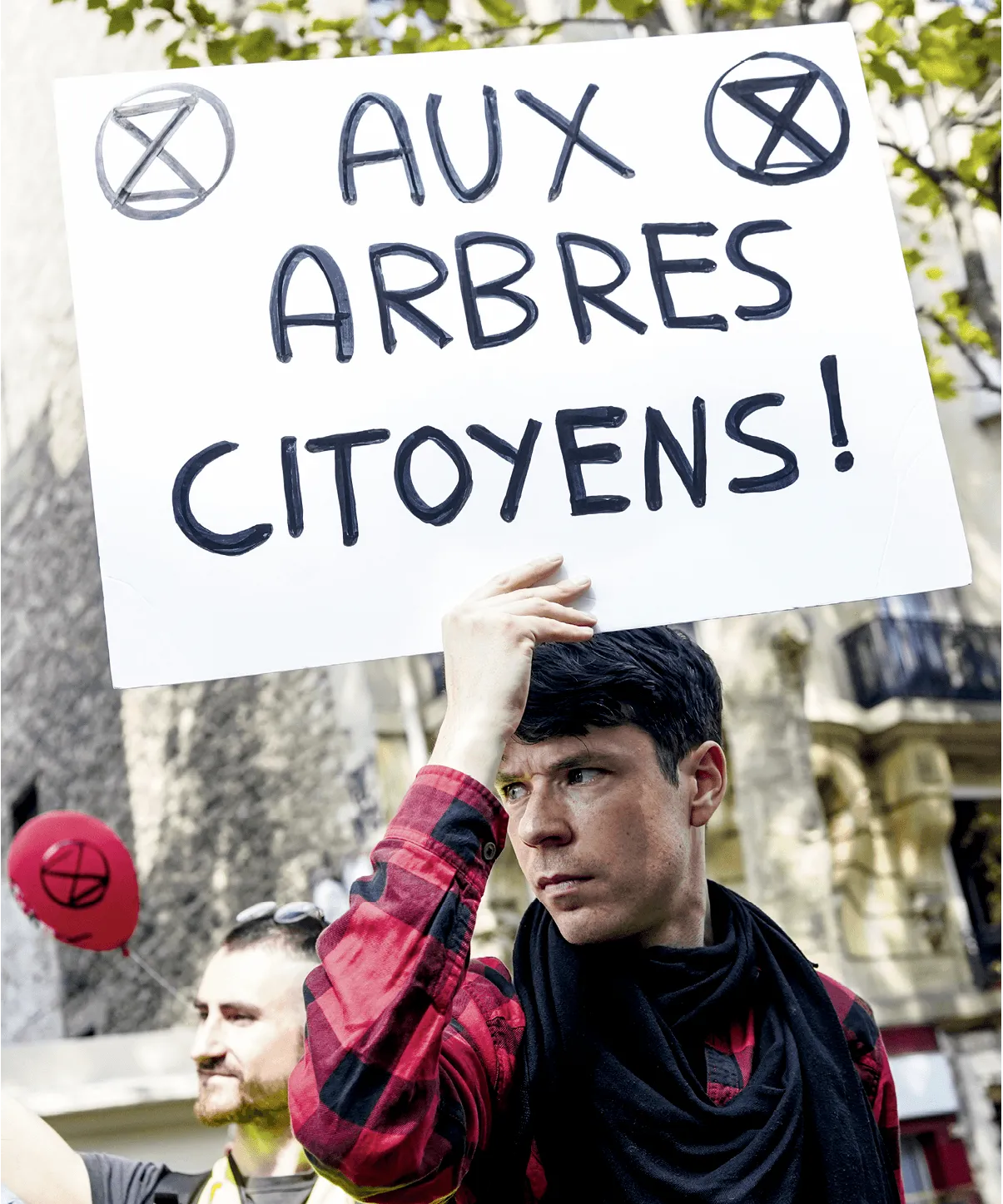 Photographie d'un manifestant Extinction Rebellion tenant une pancarte &quotAux arbres citoyens !". 