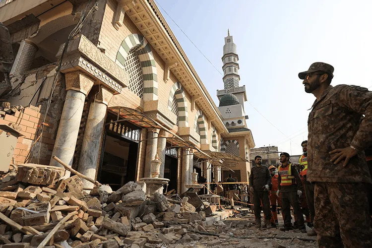 Photographie de décombres d'une mosquée détruite à Peshawar, Pakistan. Des soldats et secouristes évaluent les dégâts.