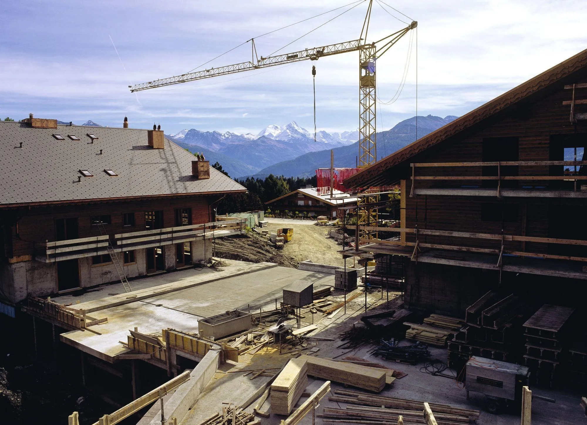 Construction d'un village de vacances dans les Alpes suisses. Cela implique d'acheminer des matériaux et de créer des réseaux d'électricité, d'adduction d'eau, de traitement des eaux usées et des déchets