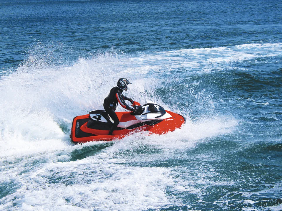 Photographie d'un homme conduisant un jet-ski rouge et blanc sur l'eau.  Vitesse et éclaboussures.