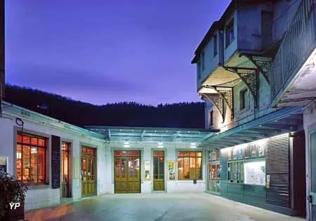 Photographie nocturne d'un bâtiment, La Fraternelle, avec une architecture élégante et des lumières chaleureuses.  L'espace semble être un lieu culturel ou communautaire.