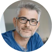 Photographie portrait d'Arthur, homme aux cheveux gris et lunettes, souriant légèrement.