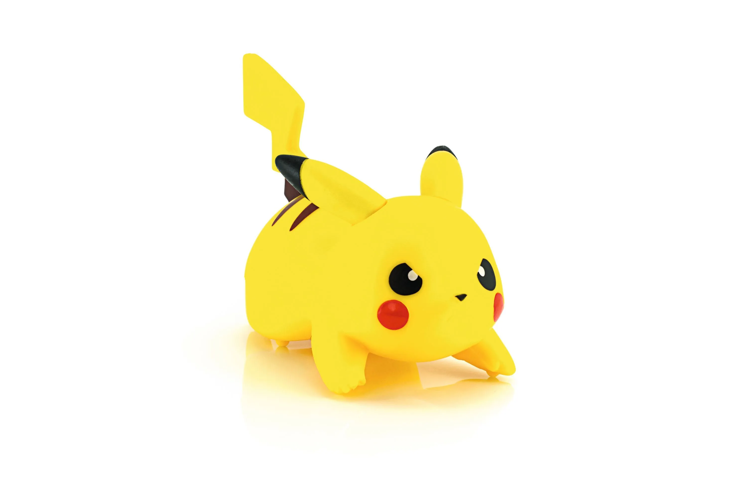 Photographie d'un jouet Pikachu, personnage Pokémon jaune, en position accroupie, sur fond blanc.