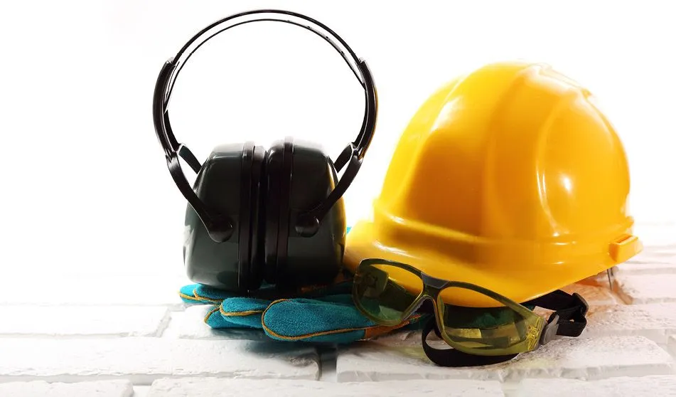 Photographie d'équipements de protection individuelle : casque jaune, casque anti-bruit et lunettes de sécurité sur gants.