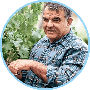 Photographie d'un viticulteur retraité souriant près de sa vigne.