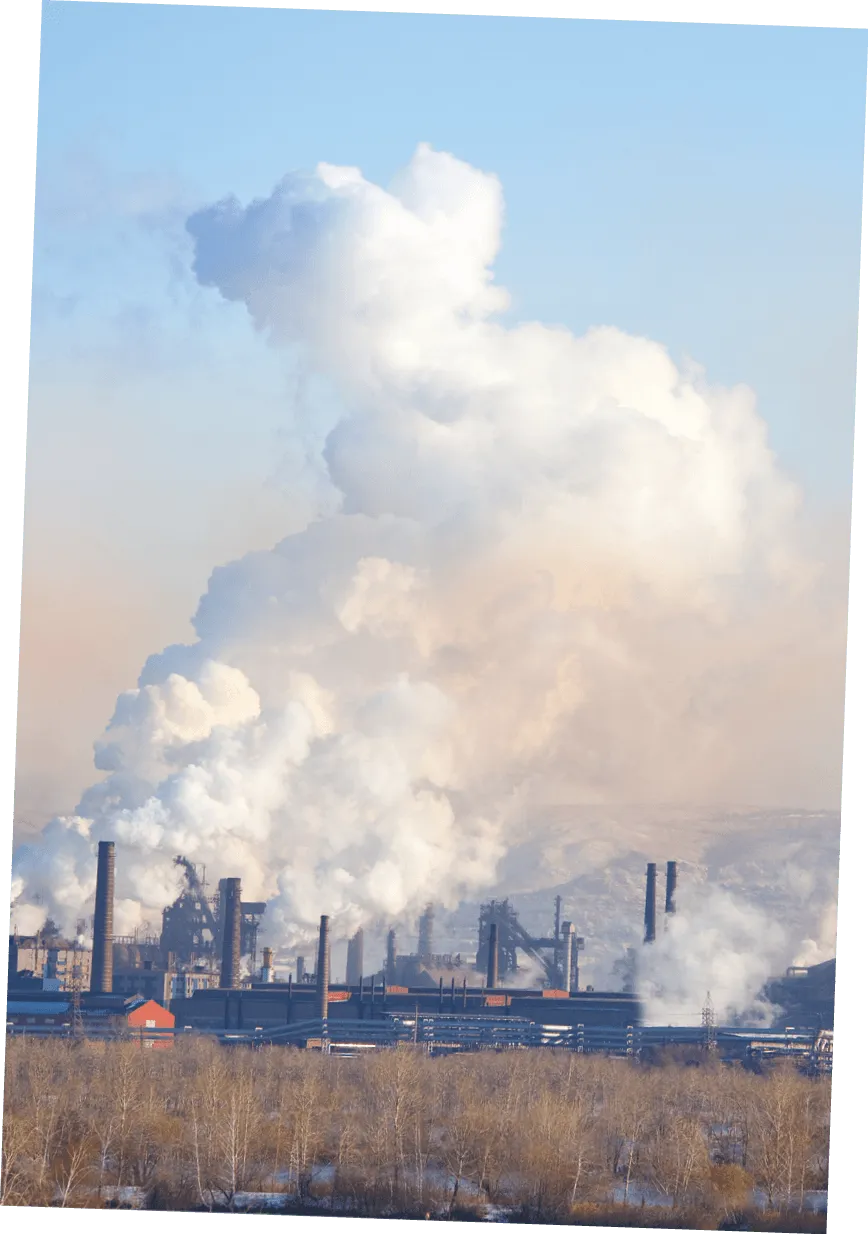 Photographie d'une usine émettant une épaisse fumée blanche dans le ciel. Pollution industrielle.