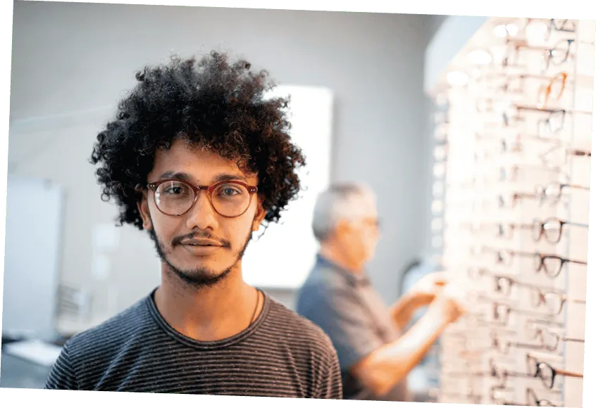 Photographie d'un jeune homme aux cheveux crépus portant des lunettes, travaillant dans un magasin d'optique.