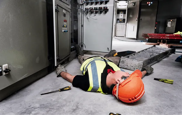 Photographie d'un ouvrier inconscient gisant au sol près d'un tableau électrique, accident du travail.