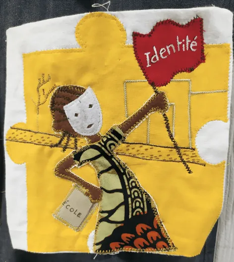 Appliqué textile représentant une fillette tenant un drapeau &quotIdentité", évoquant les droits de l'enfant et l'importance de l'éducation.