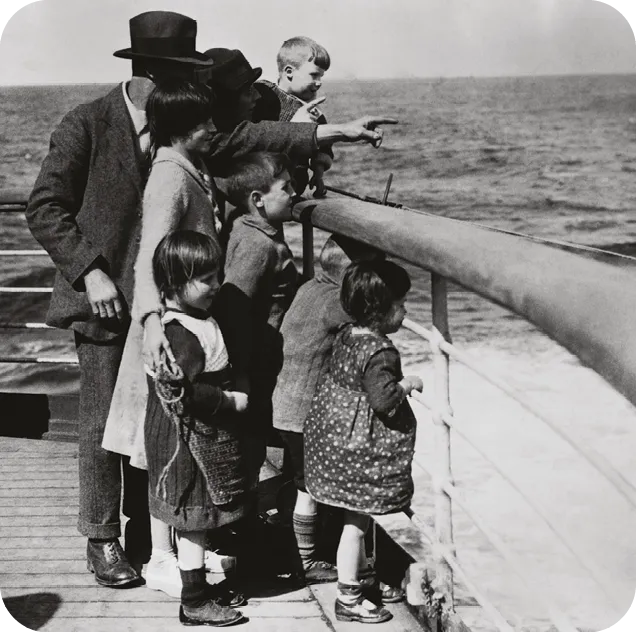 An emigrant family sights their destination, Canada, from the ship deck.