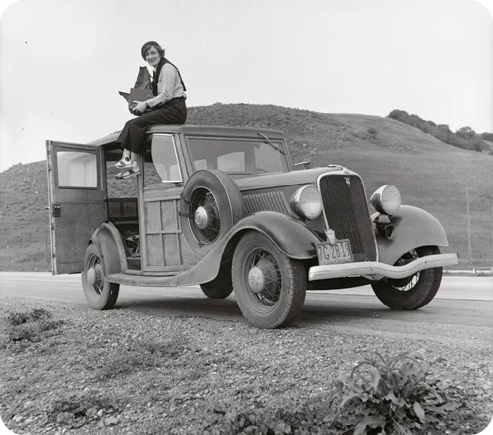 Dorothea Lange sitting on the roof of her Ford
Model T, holding her Graflex camera, 1930.