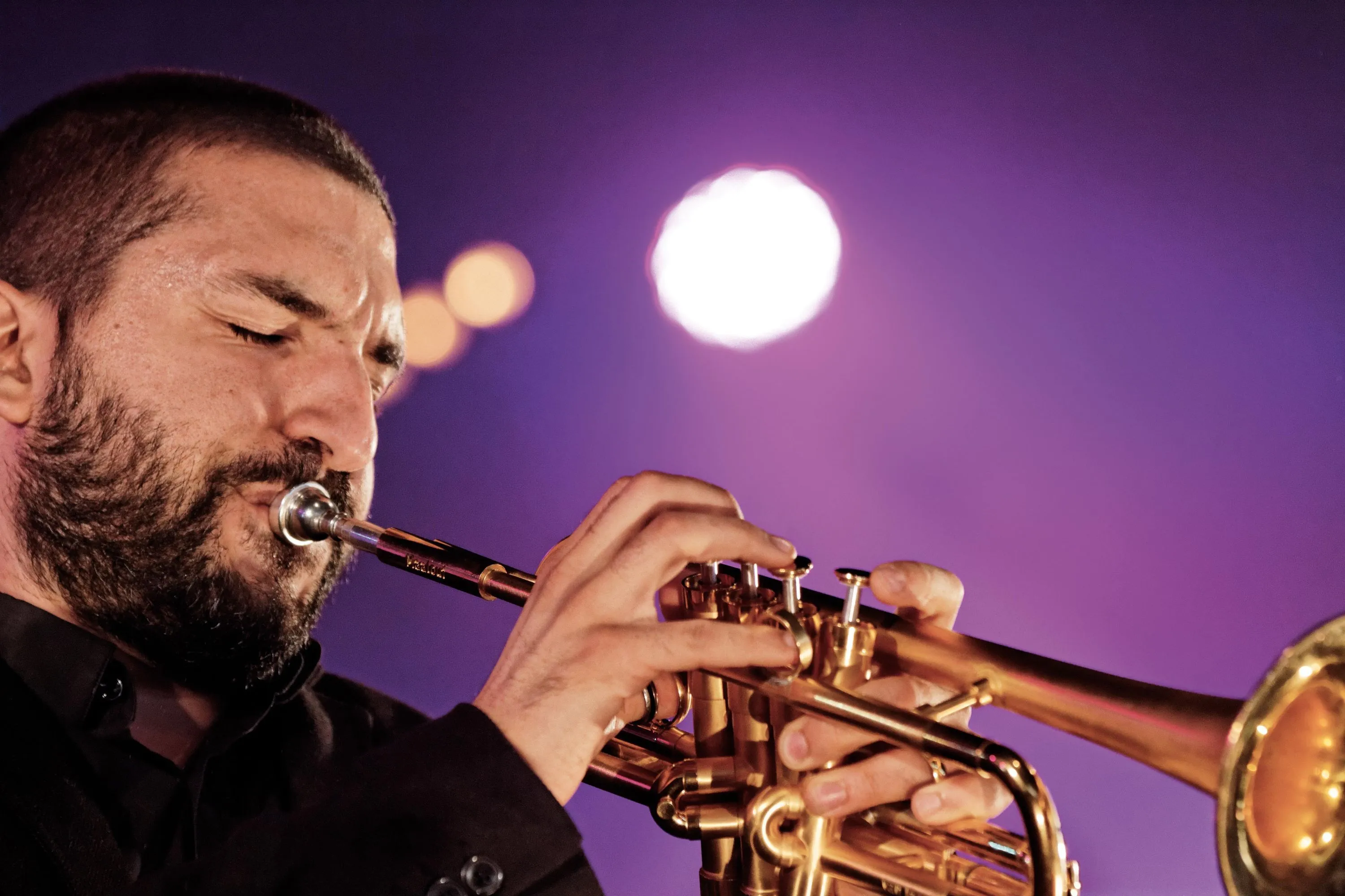 Photographie d'Ibrahim Maalouf jouant de la trompette sur scène, sous des lumières violettes.