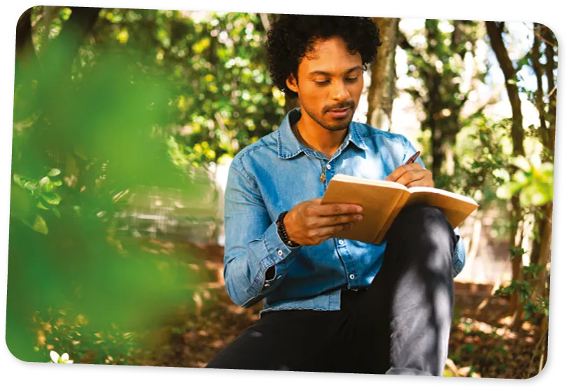 A man writing in a journal in nature.