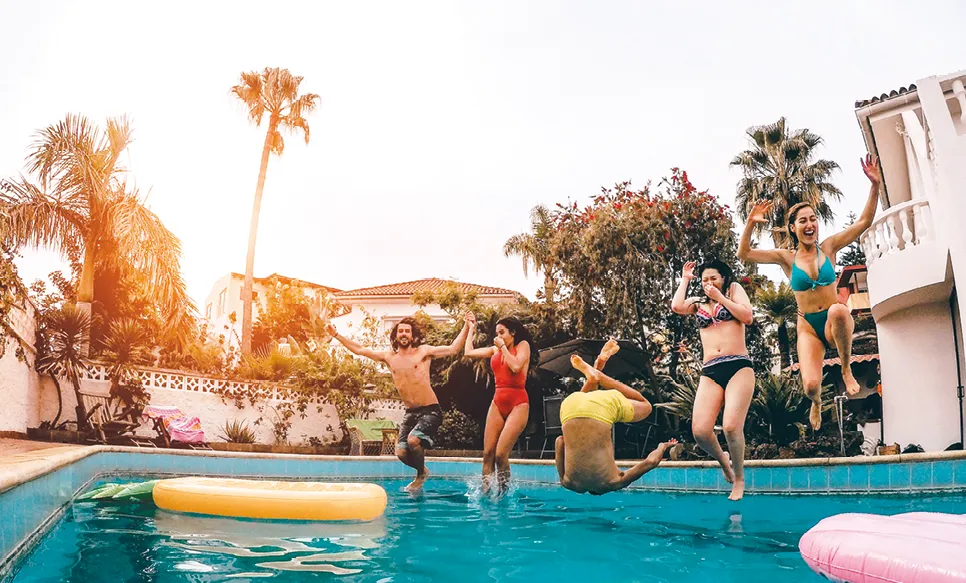 photographie d'un groupe d'amis heureux
de sauter dans la piscine au coucher du soleil