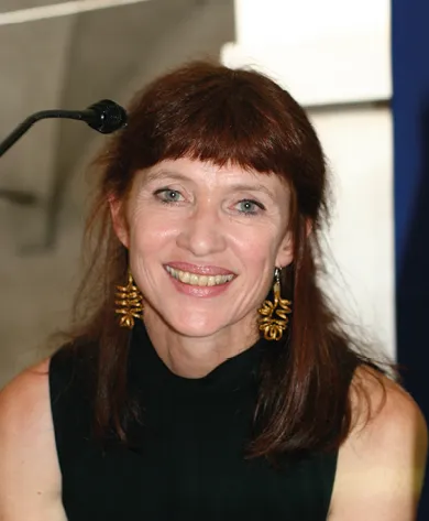 Photographie de Nancy Huston, écrivaine, souriante, portant des boucles d'oreilles dorées.